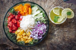Tigela colorida com arroz, legumes frescos e bebida com limão, ideal para uma refeição nutritiva no pós-parto.