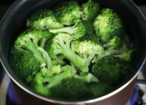 A imagem mostra brócolis fresco sendo cozido em uma panela com água, preservando sua cor verde intensa e nutrientes essenciais. Este vegetal é uma excelente fonte de fibras, vitaminas e minerais, perfeito para compor refeições leves, saudáveis e nutritivas. Uma opção versátil que pode ser servida como acompanhamento ou incorporada a diversas receitas.