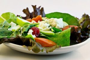 Prato de salada fresca com folhas verdes, frutas e queijo, ideal para uma alimentação balanceada no pós-parto.