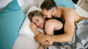 Homem e mulher deitados juntos na cama, sorrindo e aproveitando um momento íntimo e feliz