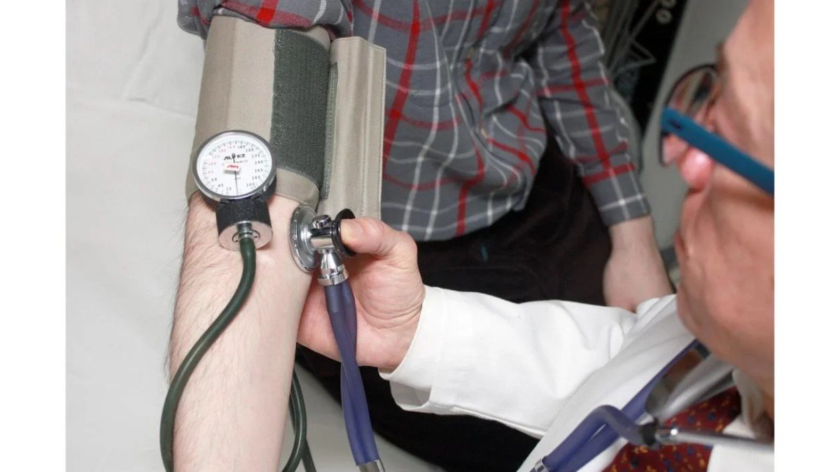 Médico medindo a pressão arterial de um paciente durante consulta
