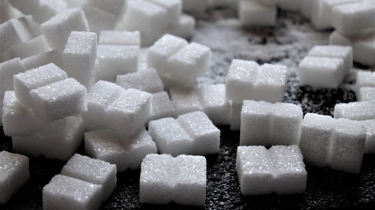 Cubos de açúcar branco espalhados sobre uma superfície escura