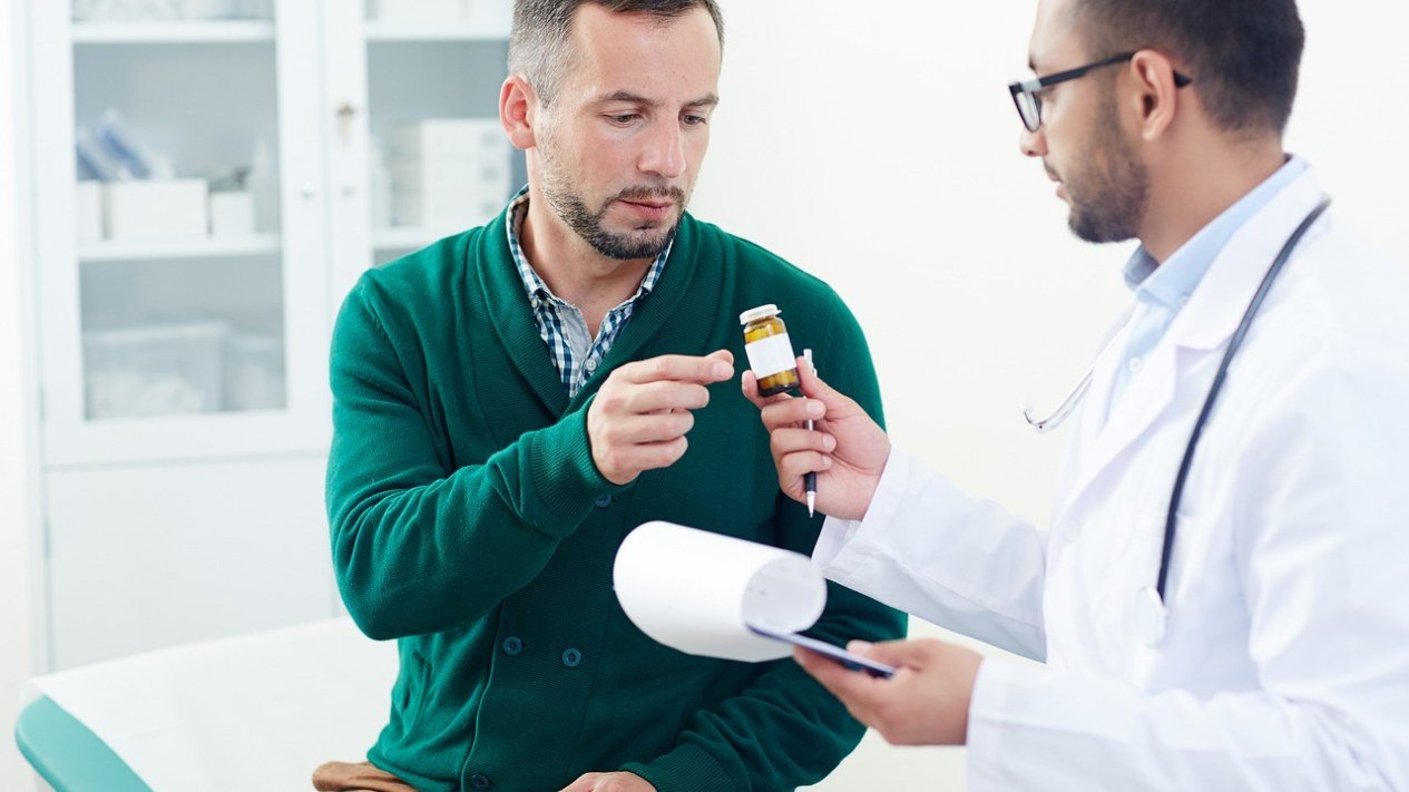 Médico e paciente conversam sobre um medicamento durante uma consulta em consultório