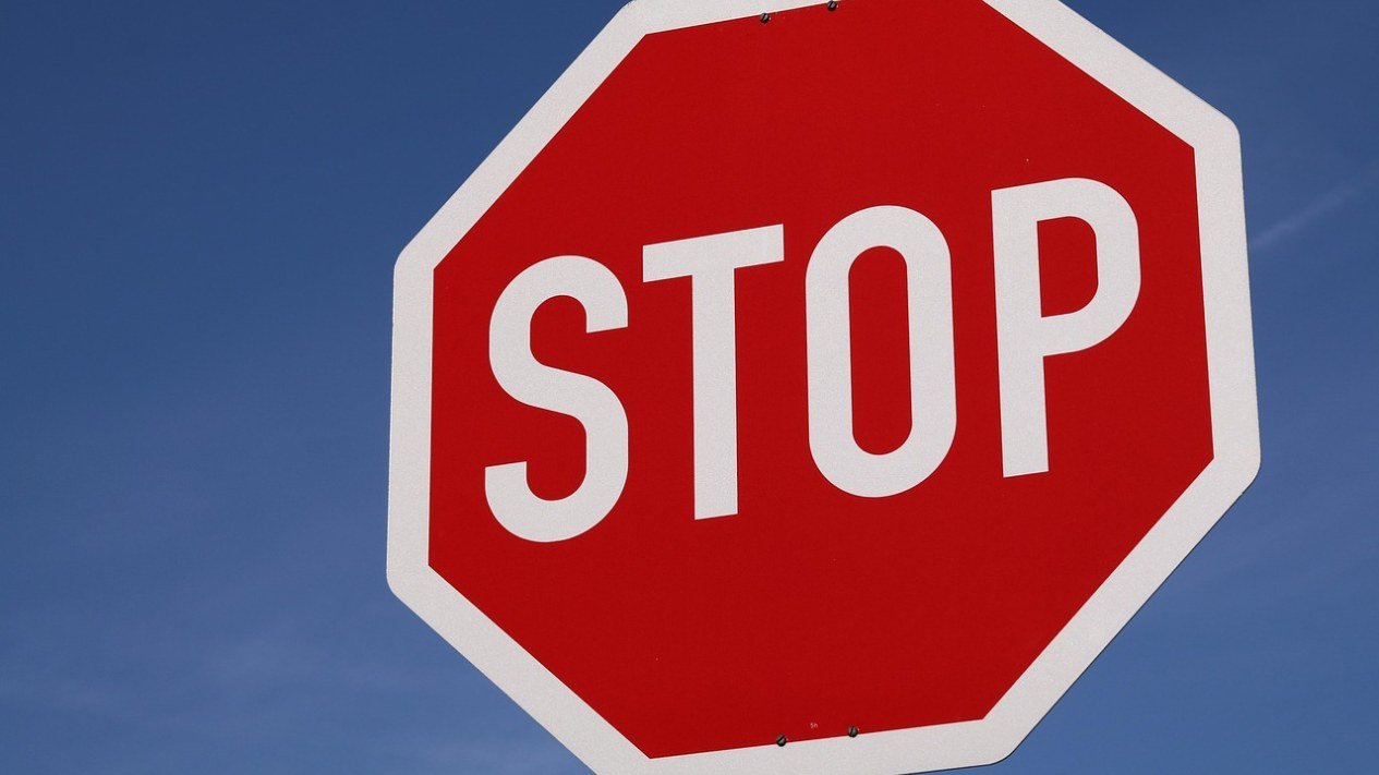Placa vermelha com a palavra STOP contra o céu azul, simbolizando a proibição da caneta T36