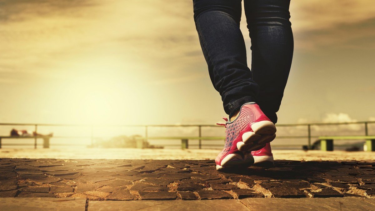Pessoa caminhando ao ar livre com tênis rosa, exemplo de atividade física para emagrecer com saúde