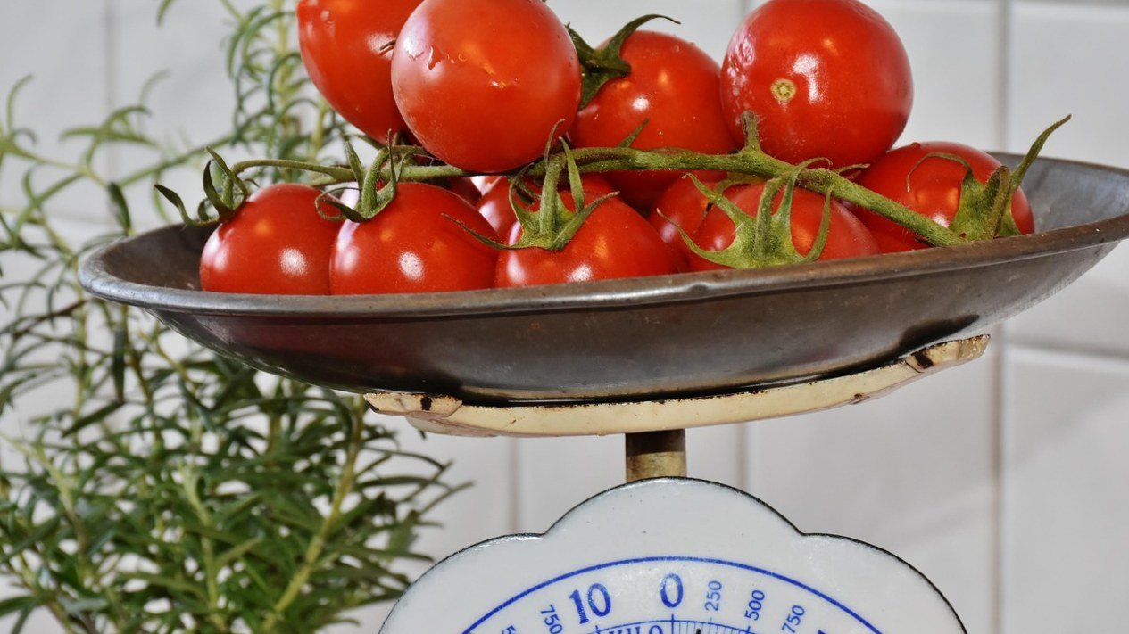 Tomates frescos sobre uma balança de cozinha antiga, ilustrando a dieta isocalórica