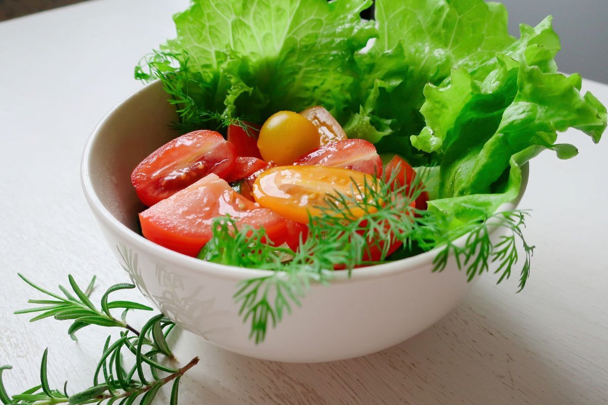 Tigela de salada fresca com alface, rodelas de tomate e ervas