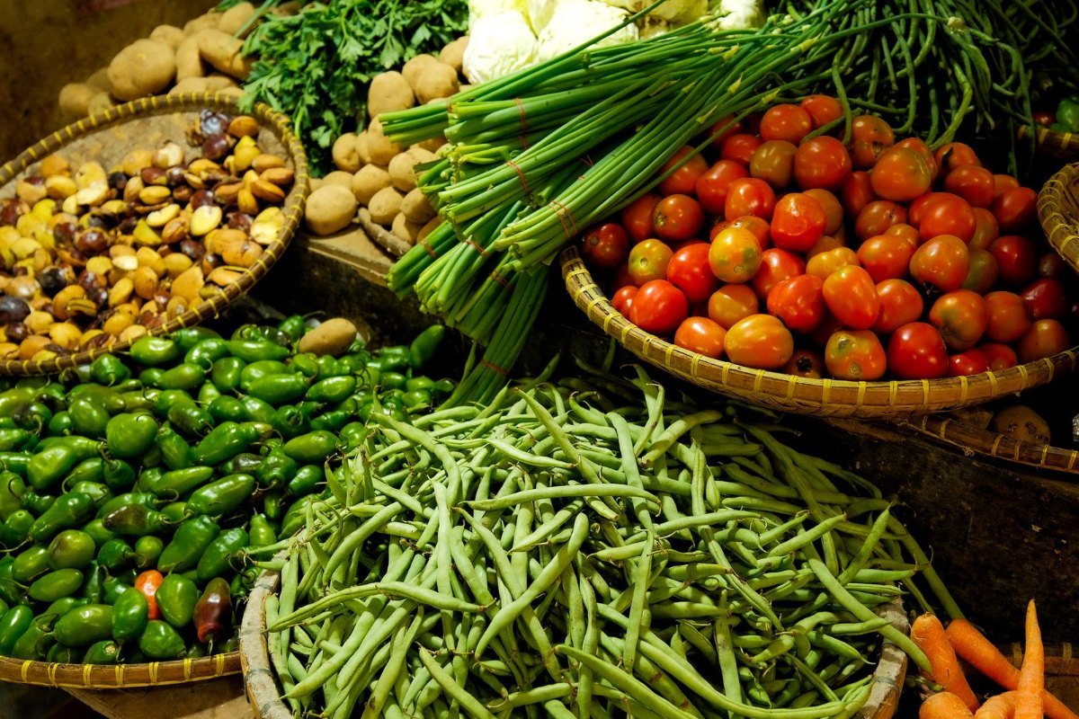 Cestas de tomates, vagens, cebolinha e outros legumes frescos em uma feira